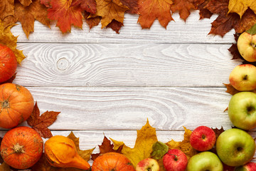 Naklejka na ściany i meble Autumn leaves, apples and pumpkins over wooden background