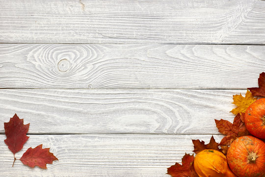 Autumn leaves and pumpkins over old wooden background