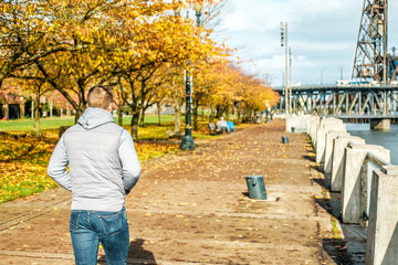 Man walking along the riverwalk in Portland city at autumn