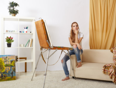 Painter female with wooden sketchbook sitting on sofa and painting