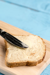 Closeup macro bread coated with butter on the wooden board with knife