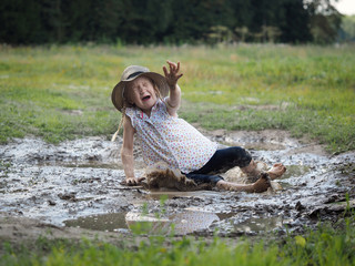 child falls in a puddle. Field. Rural road, mud