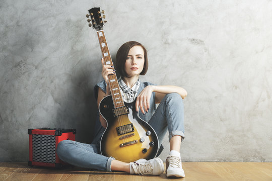 Pretty woman with guitar in studio