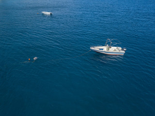 Vista aerea di una barca ormeggiata che galleggia su un mare trasparente. Immersioni relax e vacanze estive