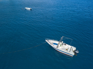 Vista aerea di una barca ormeggiata che galleggia su un mare trasparente. Immersioni relax e vacanze estive