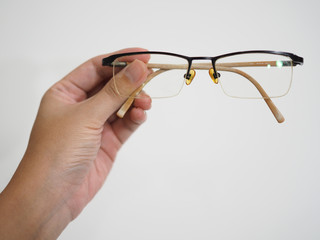 Left hand holding brown black glasses, with white background, front view