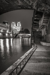 Fototapeta premium Katedra Notre Dame de Paris z brzegów Sekwany w nocy w czerni i bieli. Ile de la Cite, Paryż, Francja