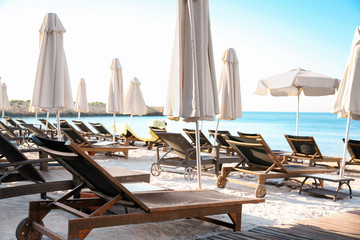 Empty sunbeds with patio umbrellas on beach