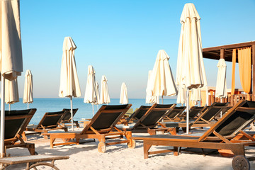Empty sunbeds with patio umbrellas on beach