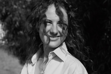 Beautiful natural fresh & fashionable outdoor black white shot of cheerful & stunning young happy woman with gorgeous smile & curvy curly long hair in oversized shirt. Youth beauty & freedom concept.