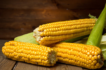 Ripe yellow sweet corn cob on a wooden table close-up