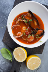 Close-up of tomato soup with vongole shells and mussels in a white bowl, view from above