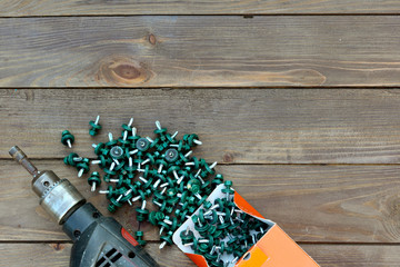 Roofing screws and a drill on a wooden table. The view from the top. Template for labor day...