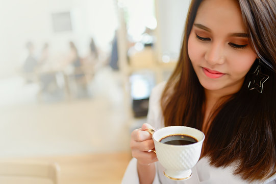 Portrait of beautiful woman holding a cup of coffee in her hand in blur background coffee shop, she drink coffee in the morning, with copy space for text