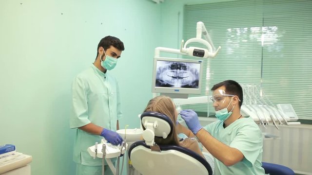 Dentist using dental curing UV lamp on teeth of patient