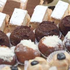 A variety of delicious cakes lined up in rows in a shop window in a cafe