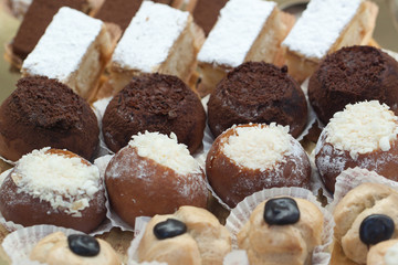 A variety of delicious cakes lined up in rows in a shop window in a cafe