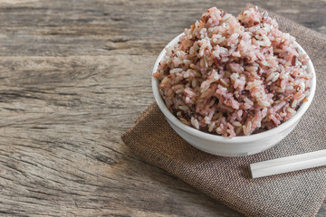 cooked mix rice in a ceramic bowl on calico fabric with old and crack wooden background. healthy food concept, copy space