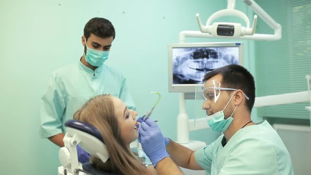 Dentist using dental curing UV lamp on teeth of patient