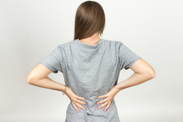  Pretty woman suffers from backache standing over gray background