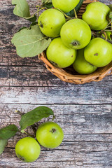  Fresh green apples with leaves in a wicker basket on a old wooden table. A new crop. The concept of a healthy diet. Top view.