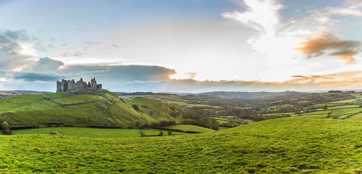 Countryside panorama with ruined castle on a hill at sunset