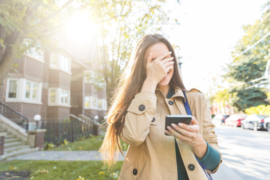 Woman With Phone Laughing And Covering Face With Hand