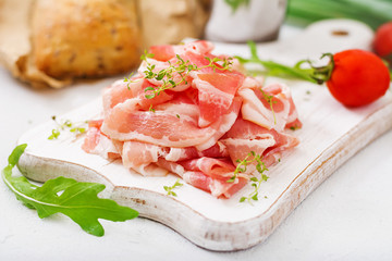 Slices of bacon on  a wooden board.