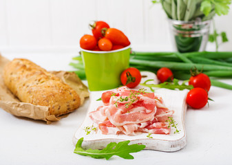 Slices of bacon on  a wooden board.