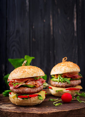 Big sandwich - hamburger burger with beef, cheese, tomato, cucumber and fried bacon.