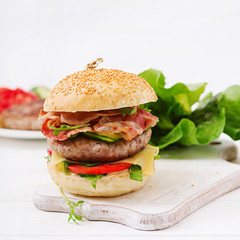 Big sandwich - hamburger burger with beef, cheese, tomato, cucumber and fried bacon.