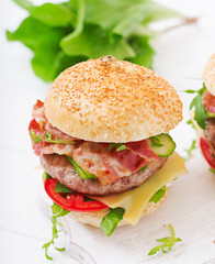 Big sandwich - hamburger burger with beef, cheese, tomato, cucumber and fried bacon.