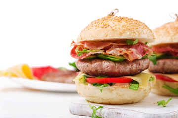 Big sandwich - hamburger burger with beef, cheese, tomato, cucumber and fried bacon.