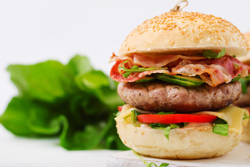 Big sandwich - hamburger burger with beef, cheese, tomato, cucumber and fried bacon.