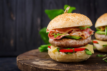 Big sandwich - hamburger burger with beef, cheese, tomato, cucumber and fried bacon.