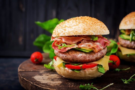 Big sandwich - hamburger burger with beef, cheese, tomato, cucumber and fried bacon.