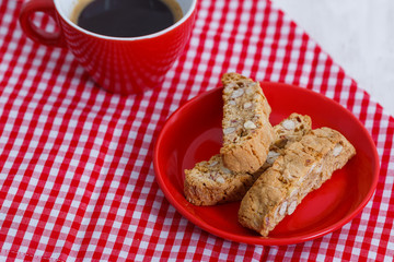 House biscuit of cantuccini or cantucci, the Italian cookies, on a saucer of red color with a cup of coffee on a white background