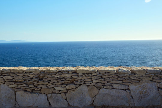 Muretto di pietre con mare sullo sfondo