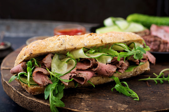 Sandwich of whole wheat bread with roast beef, cucumber and arugula