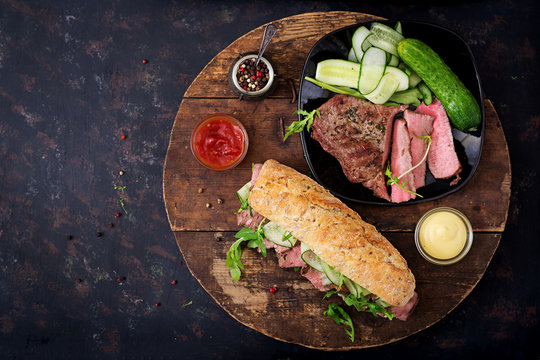 Sandwich of whole wheat bread with roast beef, cucumber and arugula. Top view. Flat lay.