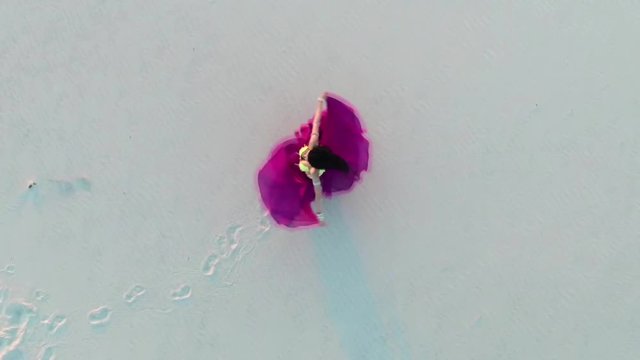 Brunette dances belly dancing in the sandy desert, her movements are unique. Aerial survey. View from above. Slow motion