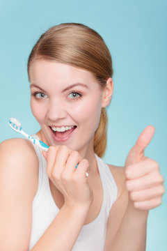 woman holds toothbrush with toothpaste cleaning teeth