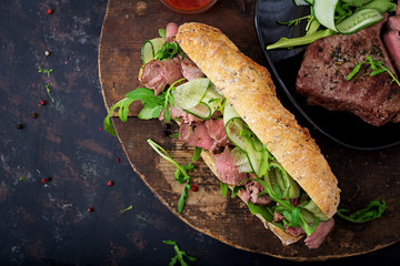 Sandwich of whole wheat bread with roast beef, cucumber and arugula. Top view. Flat lay.