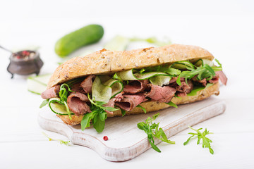 Sandwich of whole wheat bread with roast beef, cucumber and arugula.