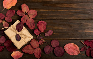 Naklejka na ściany i meble Flat lay frame of autumn crimson leaves and gift boxes on a dark wooden background.