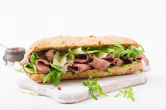 Sandwich of whole wheat bread with roast beef, cucumber and arugula.