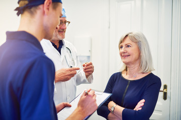 Obraz premium Medic talking to woman while assistant writing in tablet