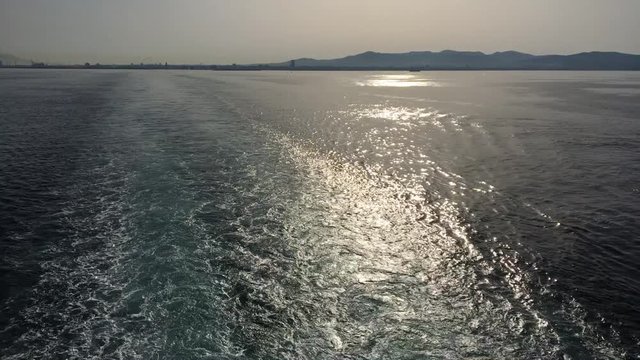 Scia del traghetto in mare al mattino controluce