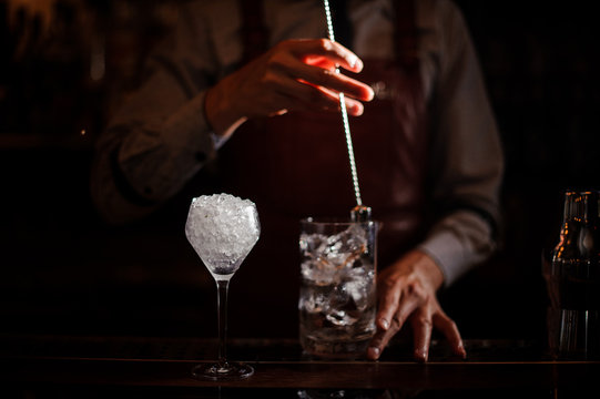 Bartender cooling out Cocktail glass mixing ice with a spoon