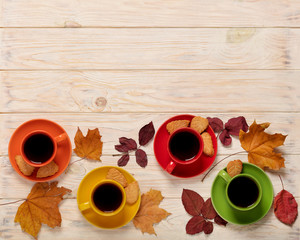 Fall concept. Cups of coffee with cookies in the form of leaves and autumn leaves on a light wooden background.